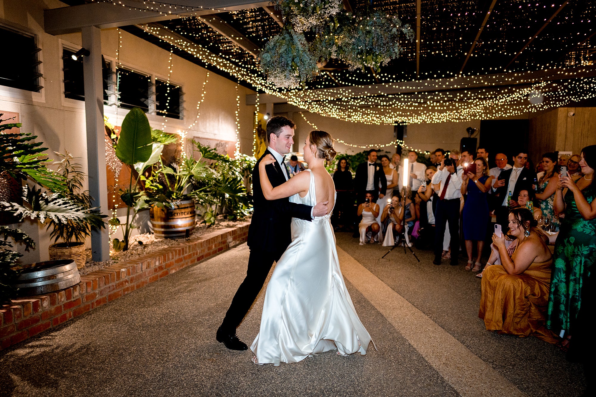 Bride and groom dancing surrounded by wedding guests at Scotchmans Hill under fairy lights.
