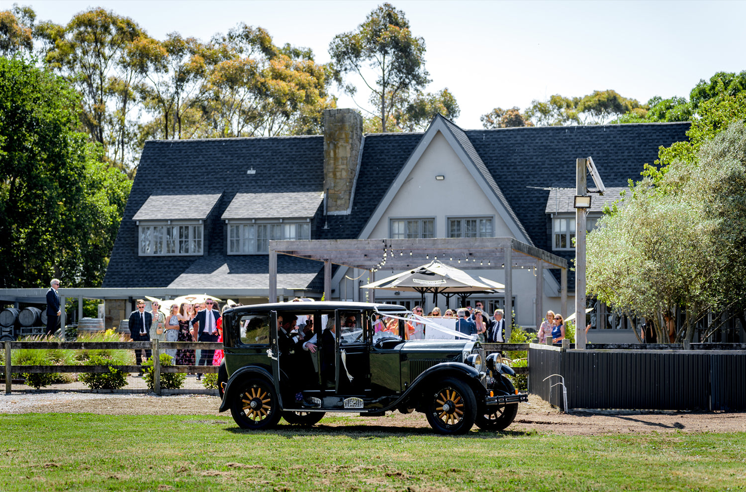 Vintage car arriving at Scotchmans Hill wedding venue with guests in front of the estate