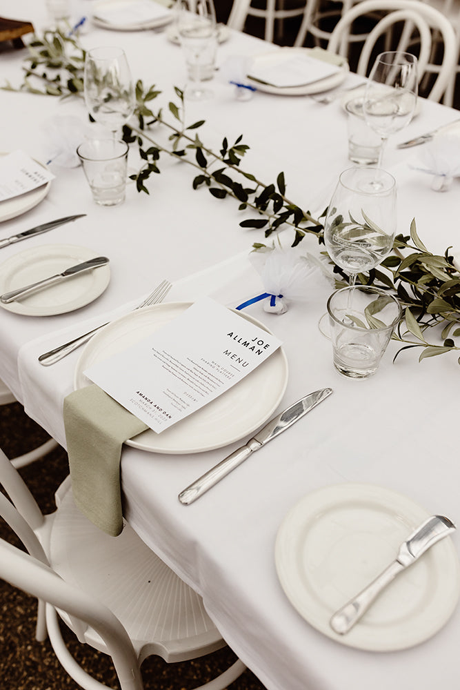 Close-up of a wedding table setting with a printed menu, glassware, and greenery at Scotchmans Hill restaurant.
