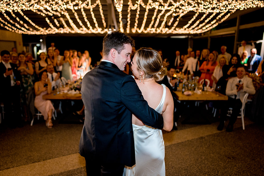 Bride and groom sharing their first dance under twinkling lights at Scotchmans Hill wedding reception.