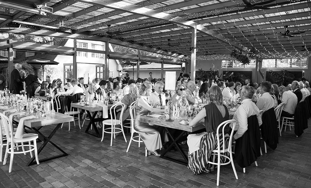 Wedding guests enjoying a seated reception dinner under fairy lights at Scotchmans Hill winery.