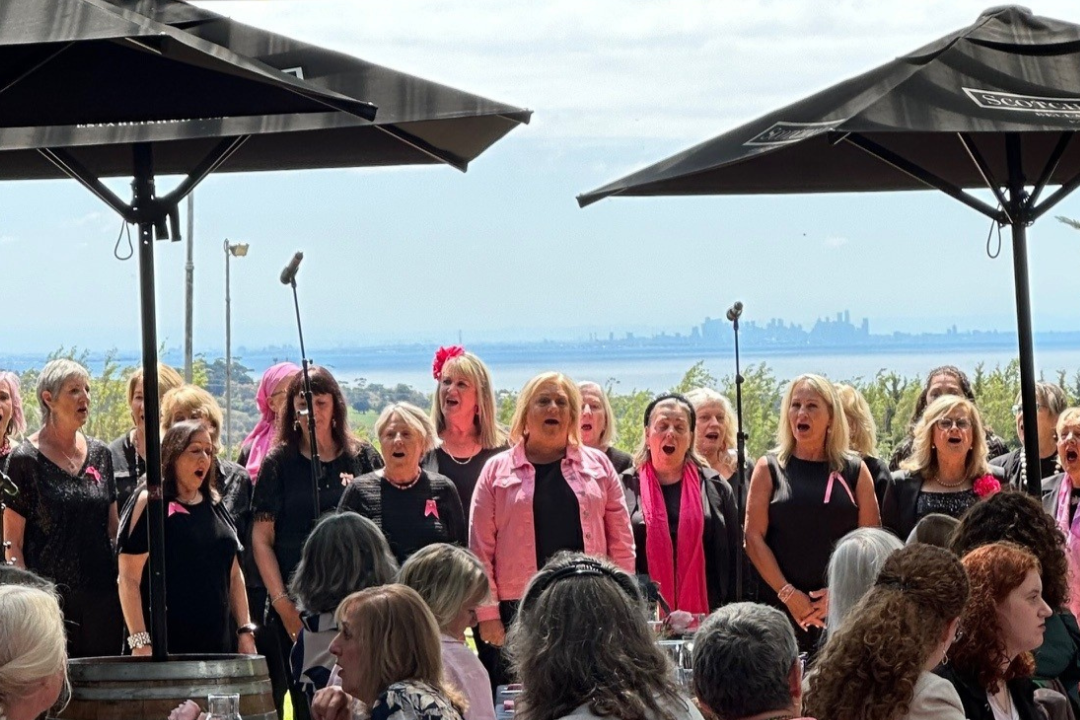 Group of women singing outdoors with a scenic background